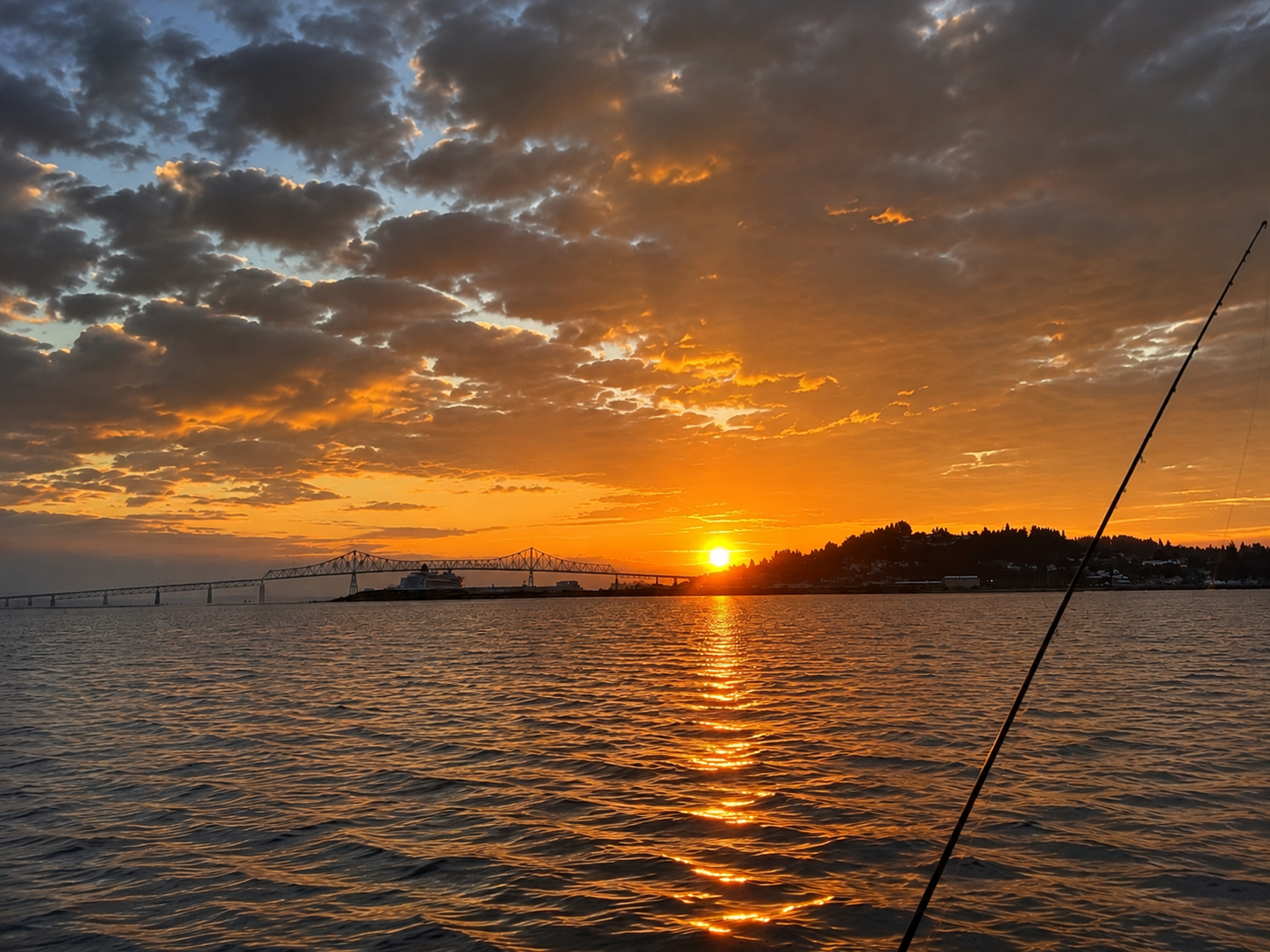 Angler holding a large salmon on an Oregon river at sunrise
